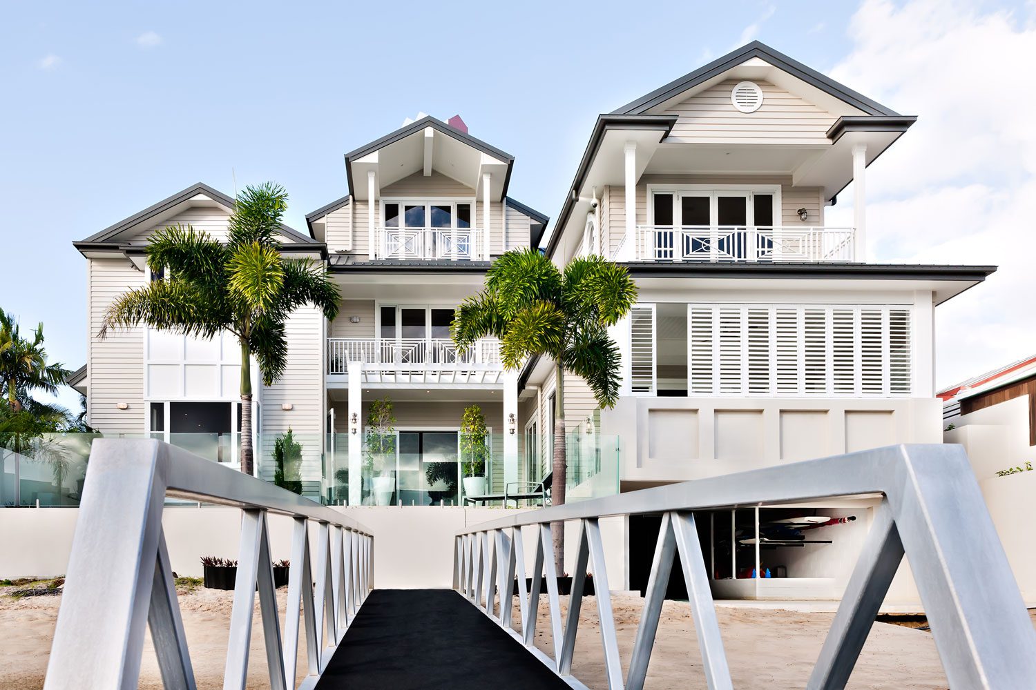 three story white home with walkway from beach